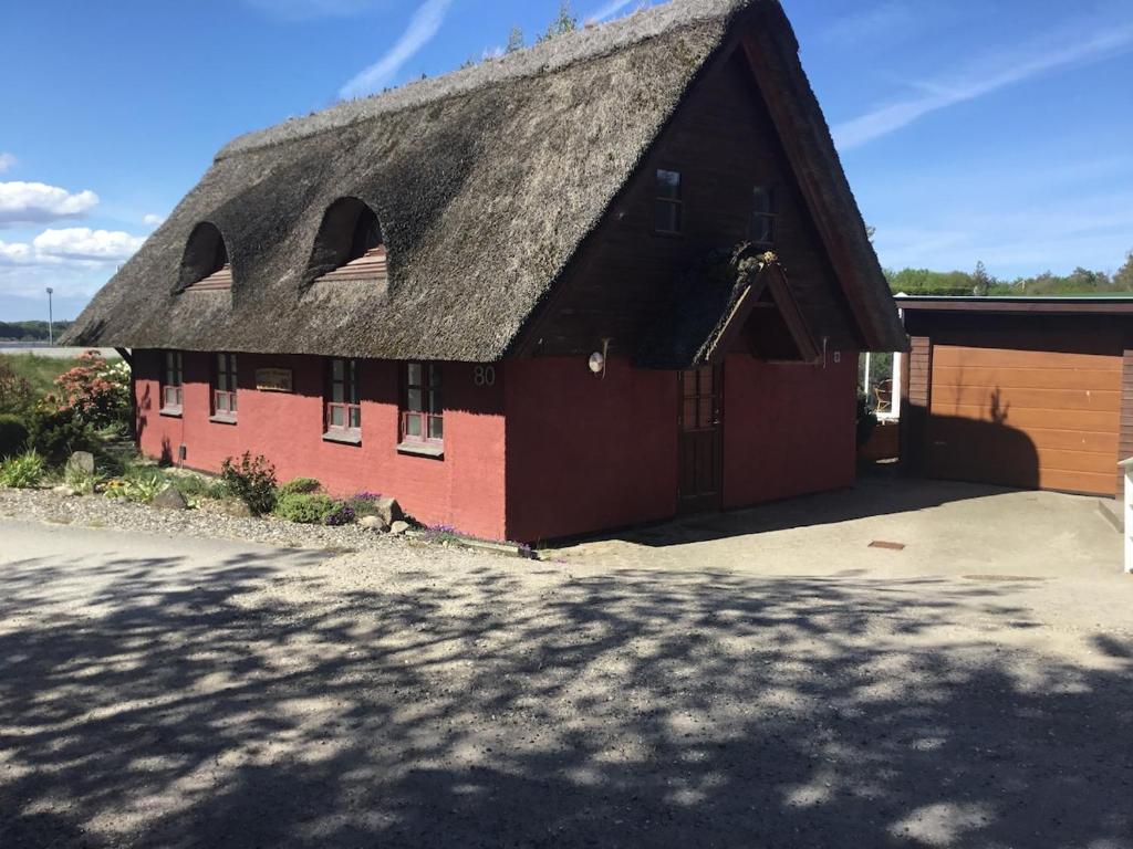 a large red barn with a thatched roof at Det Bette Hus in Fladbjerg