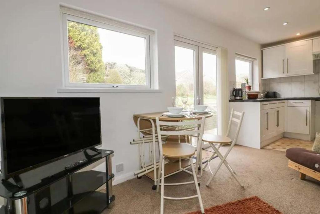 a living room with a television and a table with chairs at Bungalow - Sleeps 2 - Parking in Newquay