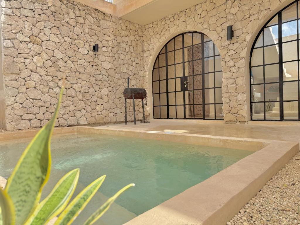 ein Schwimmbad in einem Gebäude mit einer Steinmauer in der Unterkunft Casa Bacah in Bacalar