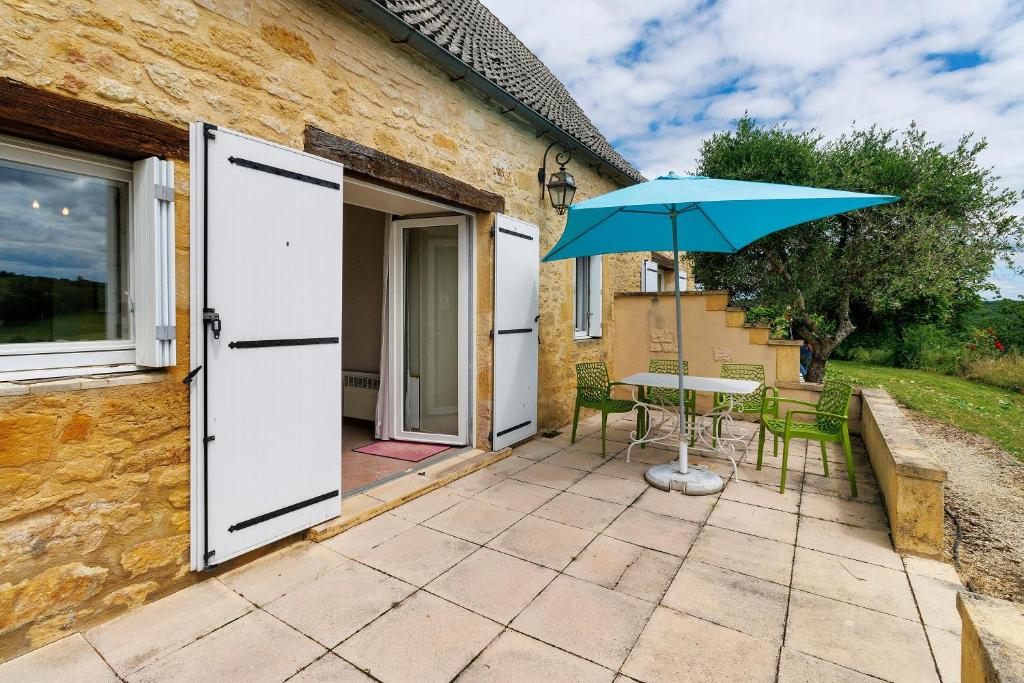 a patio with a table and an umbrella at Gite Echo in Salignac Eyvigues