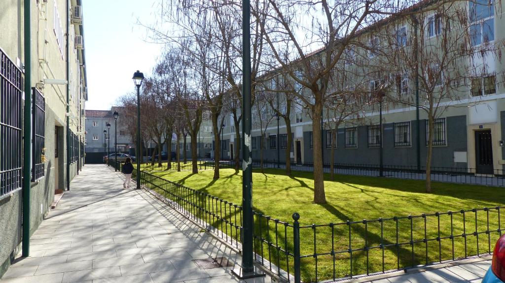 a person walking down a sidewalk next to a park at Apartamento Aluche con parking gratuito in Madrid