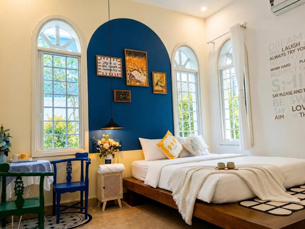 a bedroom with a large bed with a blue wall at Green Hillside Villa Hue in Hue