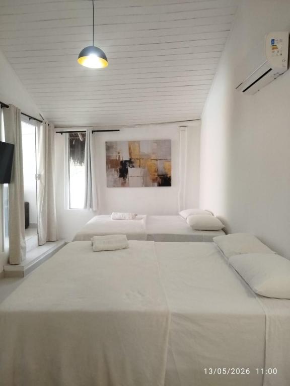 a white room with two beds and a painting at Flat Gute Morro - Praça Central in Cairu