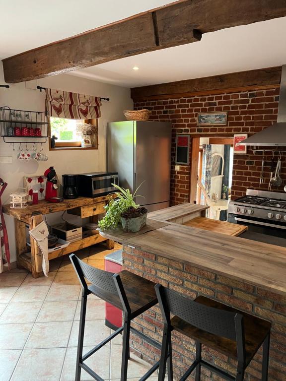 a kitchen with a counter with chairs and a refrigerator at le tilleul in Caumont