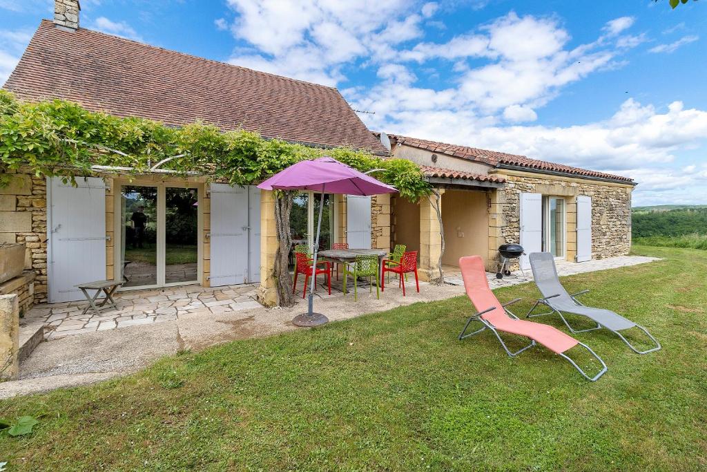 a patio with a table and chairs and an umbrella at Gite Four De Mon Père in Salignac Eyvigues