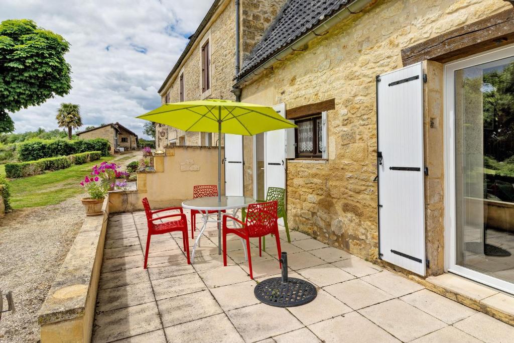 a table with two chairs and a yellow umbrella on a patio at Gîte Charly in Salignac Eyvigues