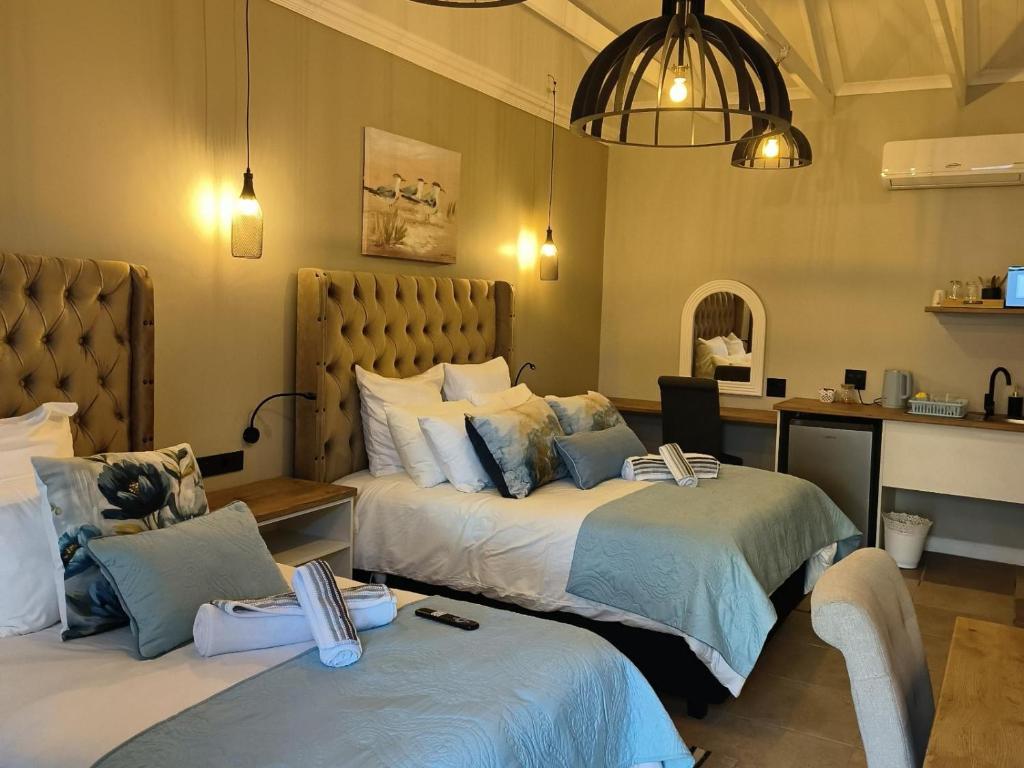 a hotel room with two beds and a desk at Bel-Air Guesthouse in Klerksdorp