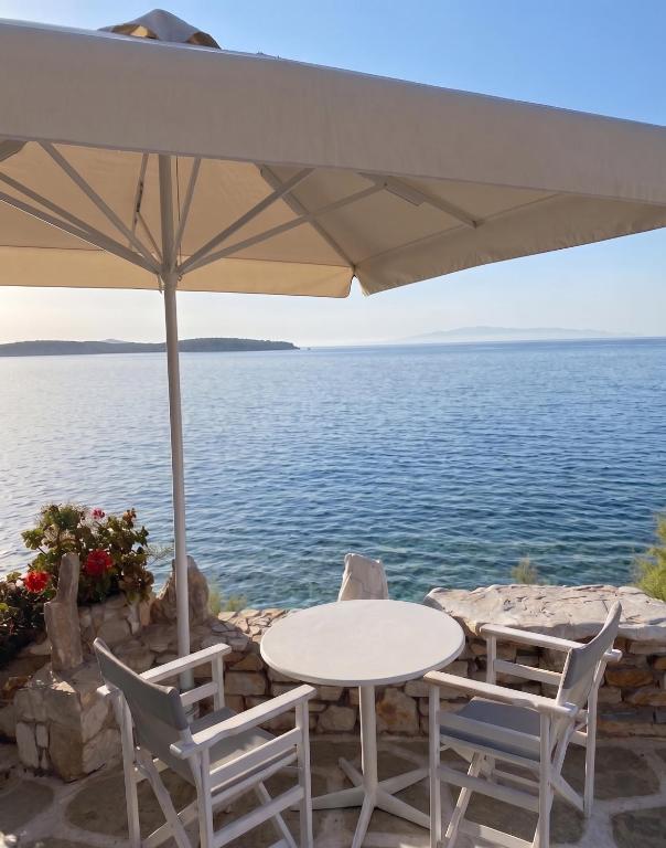 a table and chairs under an umbrella next to the water at Nissiotiko Hotel in Drios