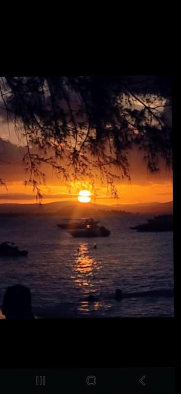 a sunset over the ocean with a boat in the water at Rainha do gelo in Barra Grande
