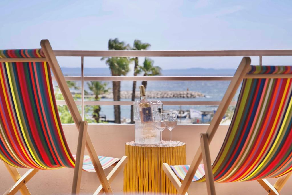 two chairs with a bottle of wine and glasses on a balcony at Hotel Espadon bleu in Le Lavandou