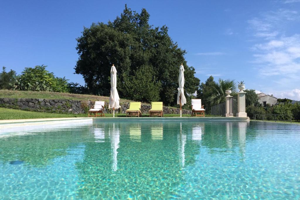 une grande piscine avec des chaises et des parasols dans l'établissement Villa Marabbecca, à Piedimonte Etneo