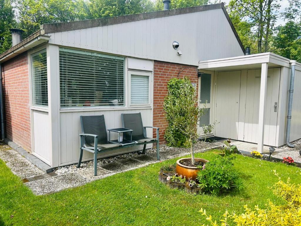 a garden with a bench and a house at De Zeebries in Warmenhuizen