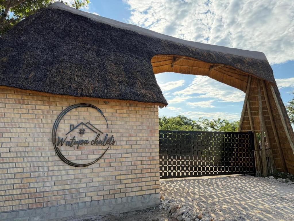 a small brick building with a thatched roof at Watupa Chalets in Rundu
