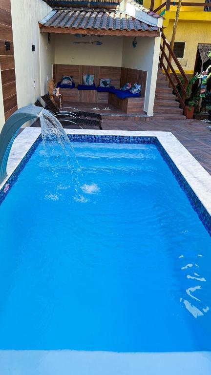 a blue swimming pool with a water fountain at Pousada Morena Raiz in Ubatuba