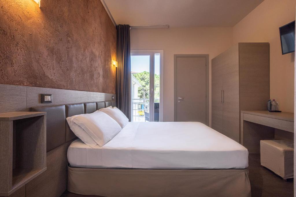 a bedroom with a large white bed and a window at Hotel Helvetia in Lido di Jesolo