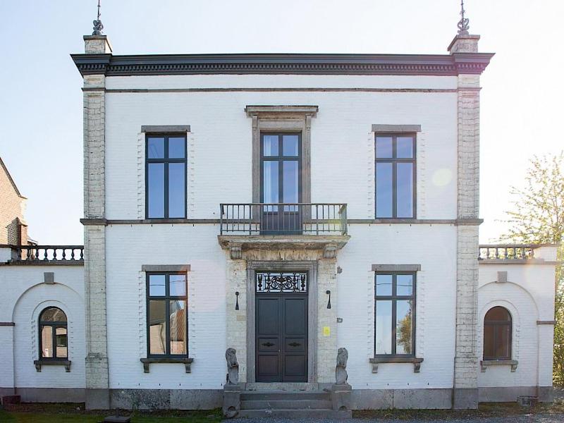 a large white house with a door and a balcony at Statig herenhuis met grote tuin en jacuzzi in Geetbets