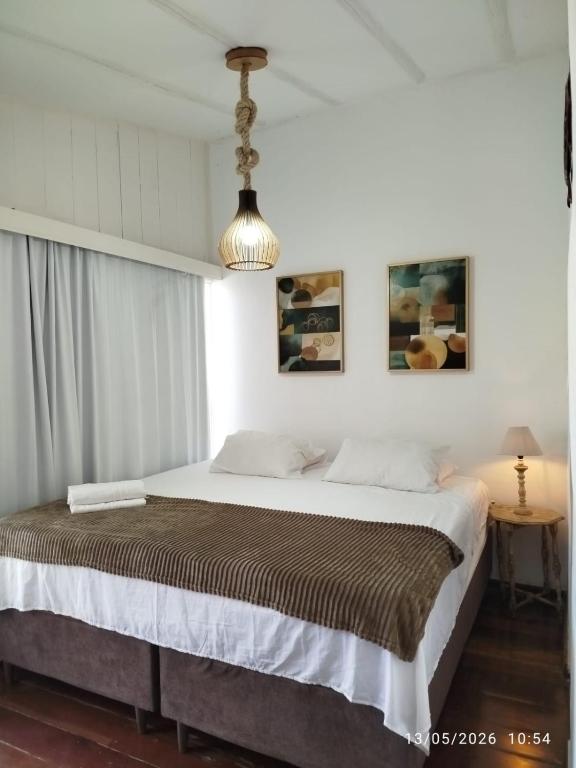 a bedroom with a large bed with white walls at Apartamento Gute Morro - Praça Central in Cairu