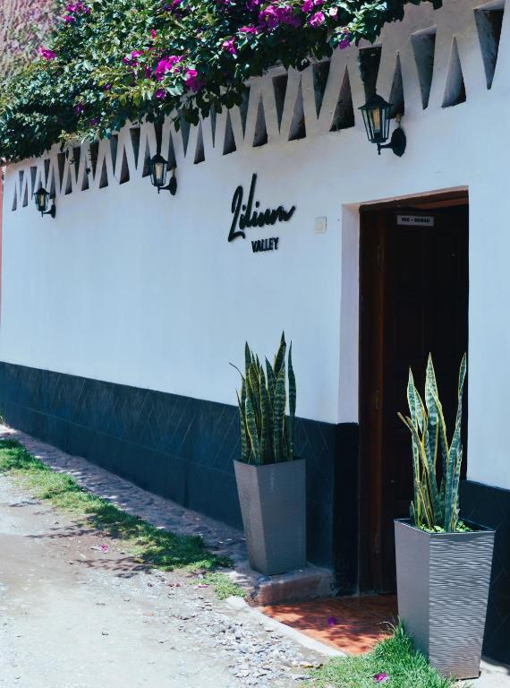 un edificio bianco con piante in vaso davanti a una porta di LILIUM VALLEY a Ollantaytambo