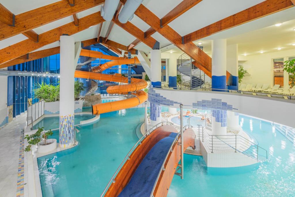 an indoor swimming pool with a water slide at Kehida Termál Resort & Spa in Kehidakustány