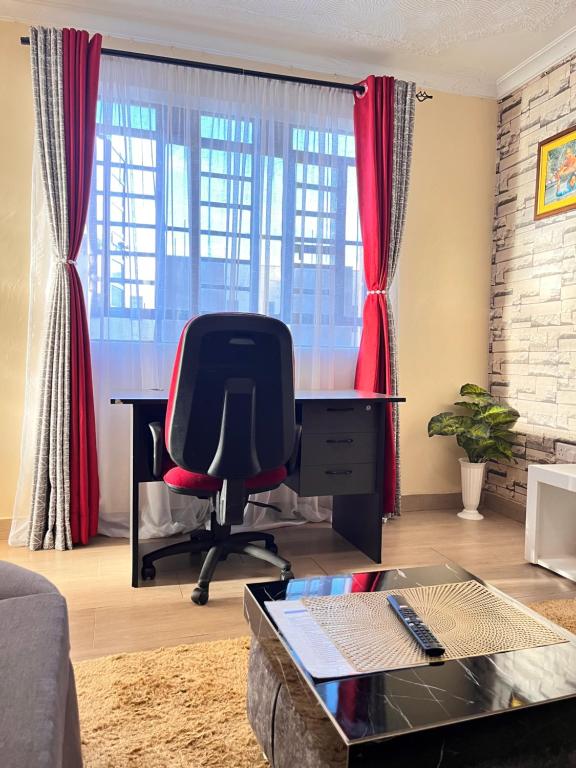 a desk and a chair in a room with red curtains at Serenity Homes in Ruiru