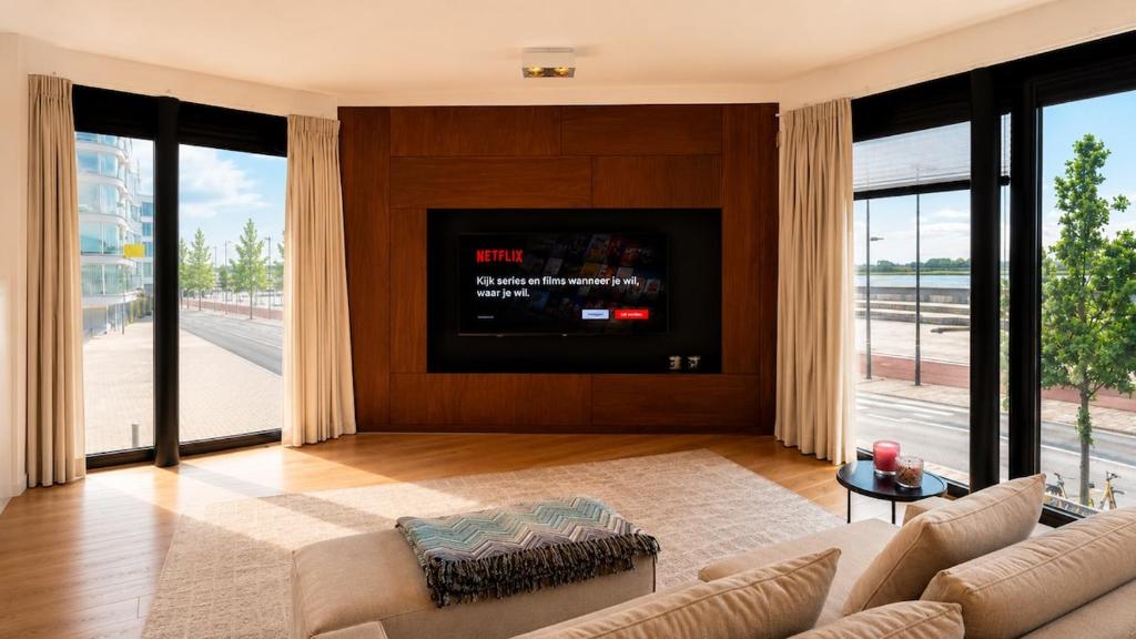 a living room with a couch and a tv at Antwerp Design Stay with Panoramic River Views in Antwerp