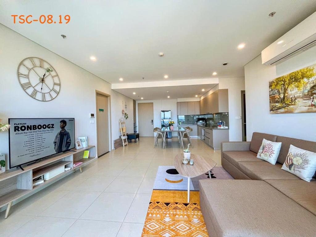 a living room with a couch and a clock on the wall at CĂN HỘ CAO CẤP THE SONG VŨNG TÀU - LUXURY APARTMENT THE SÓNG VŨNG TÀUs in Vung Tau