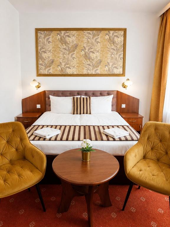 a hotel room with a bed with two chairs and a table at Pałacyk in Międzywodzie