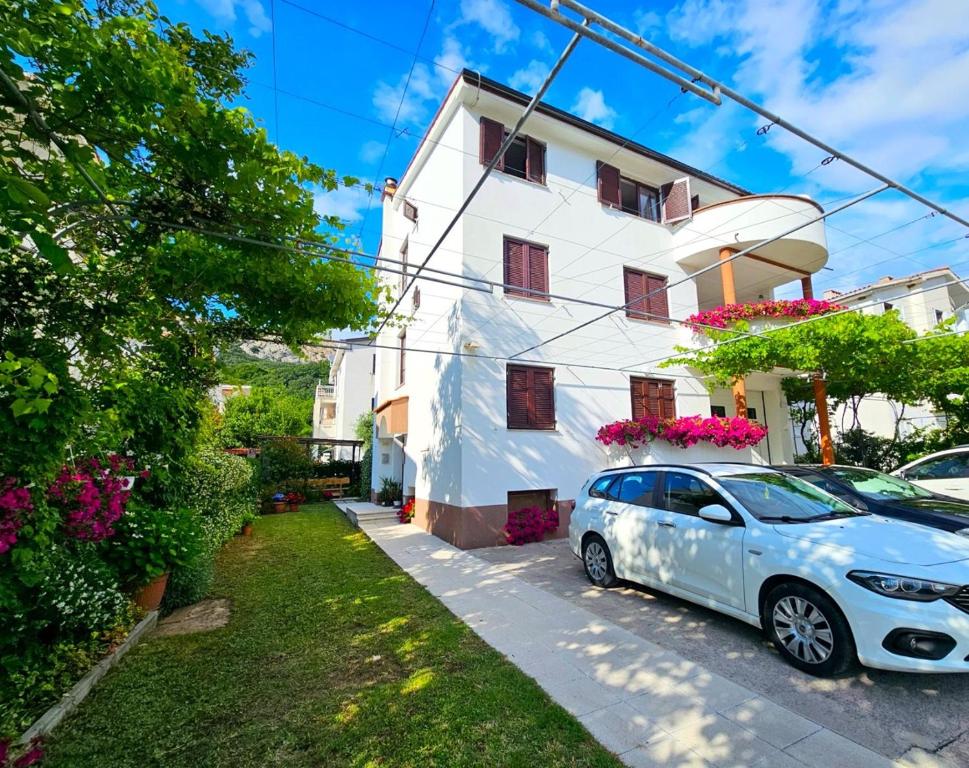 a white house with a car parked in front of it at Apartments Grozdana in Baška