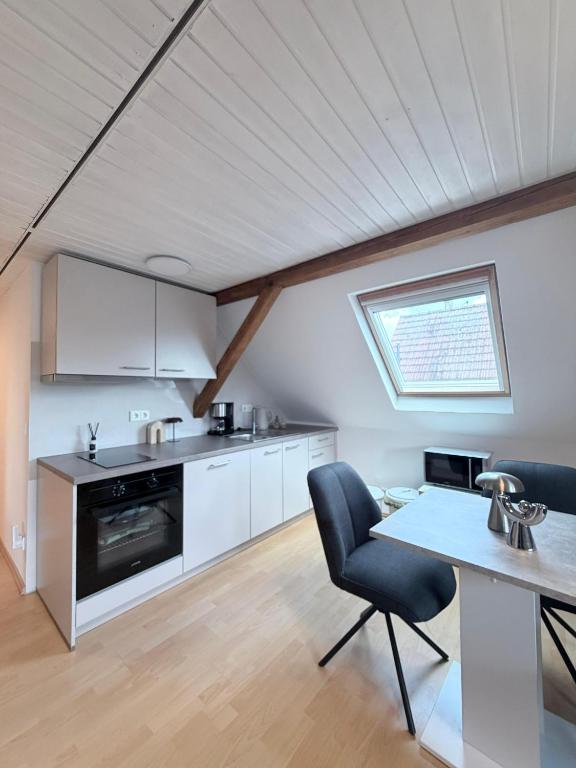 a kitchen and dining room with a table and a window at Top-floor apartment for up to 3 guests in Dreieich