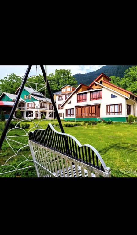 a white bench sitting in a field with houses at Hotel alpine resort pahalgam in Pahalgām