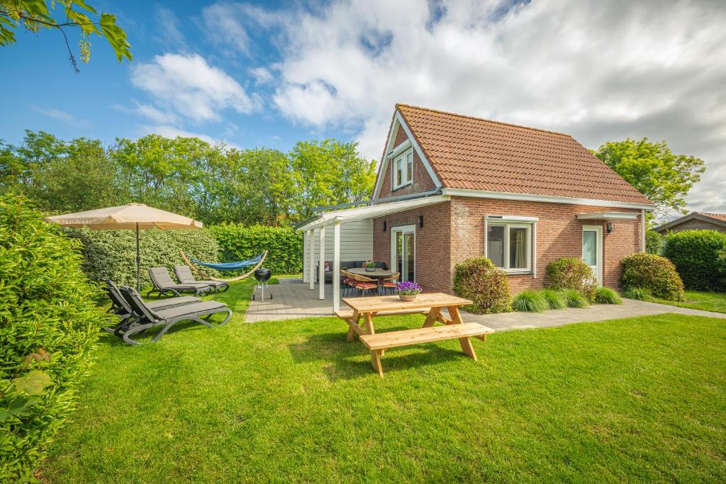 a house with a picnic table and a hammock in the yard at Lodges De Driesprong Domburg in Domburg