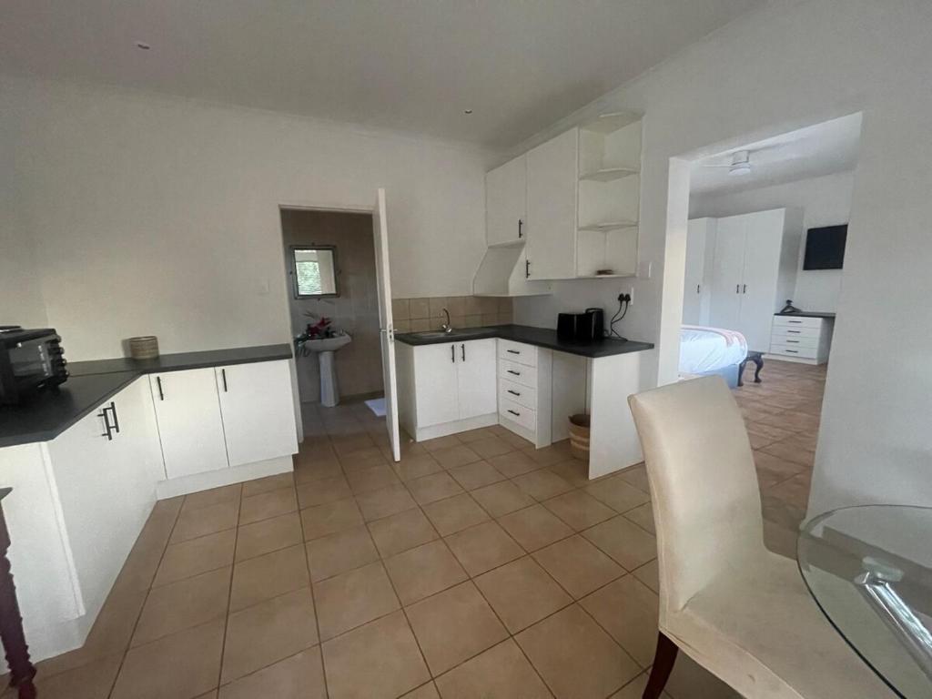 a kitchen with white cabinets and a room with a bed at Comfort & Convenience in Edenvale
