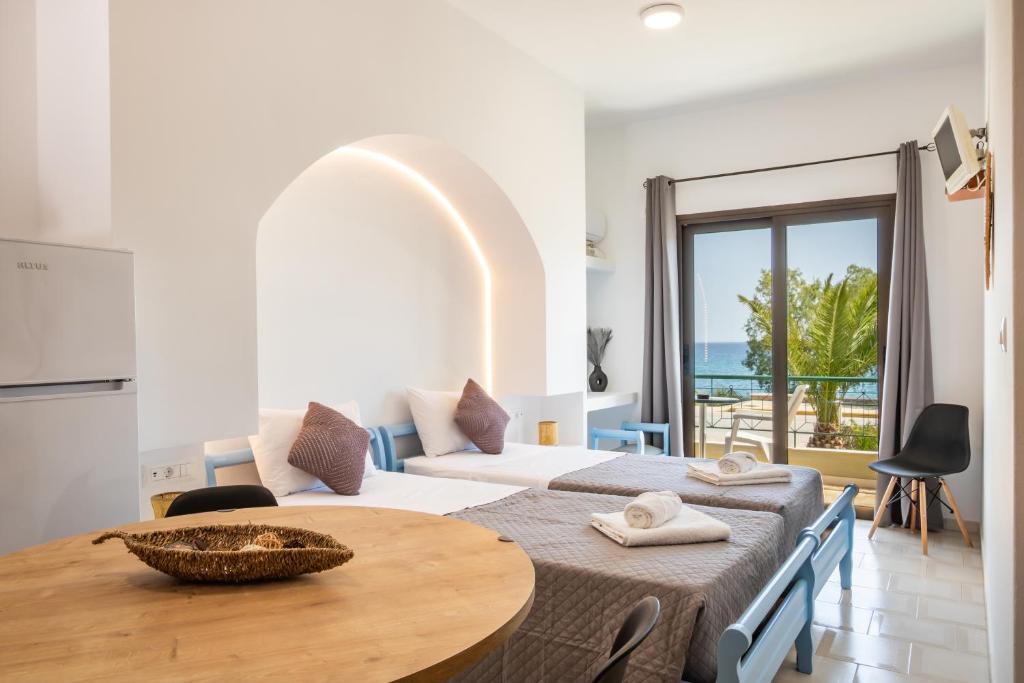 a room with two beds and a table and a kitchen at Sun Beach Apartments in Karpathos