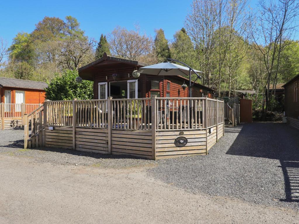 a wooden cabin with an umbrella on top of it at Badgers Hollow Lodge in Windermere