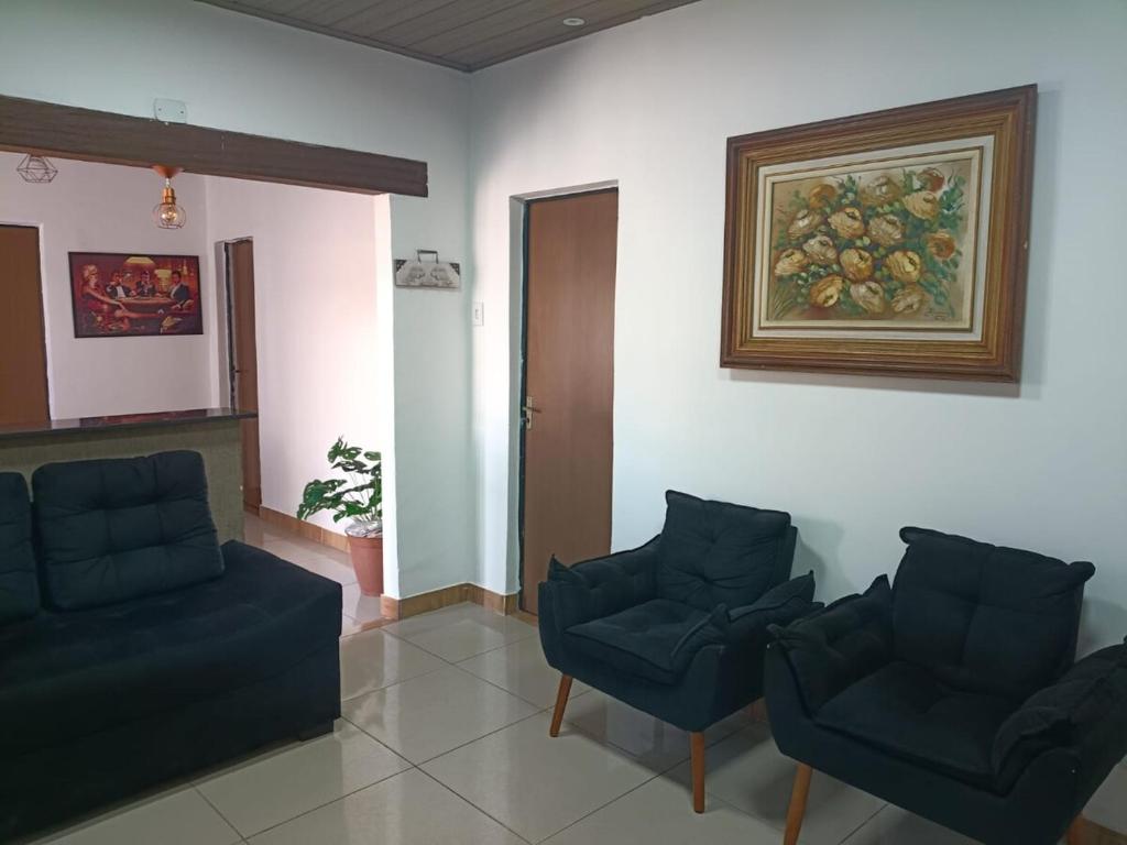a waiting room with two chairs and a painting on the wall at Casa no centro de Brumadinho in Brumadinho
