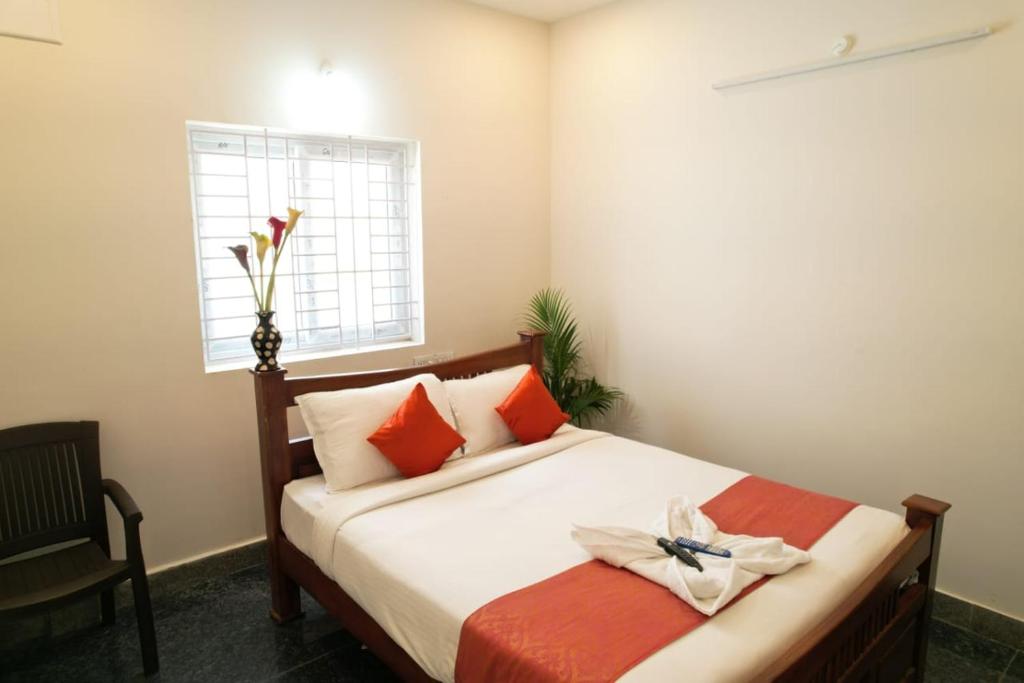 a bedroom with a bed with orange pillows and a window at Unique3 in Yercaud