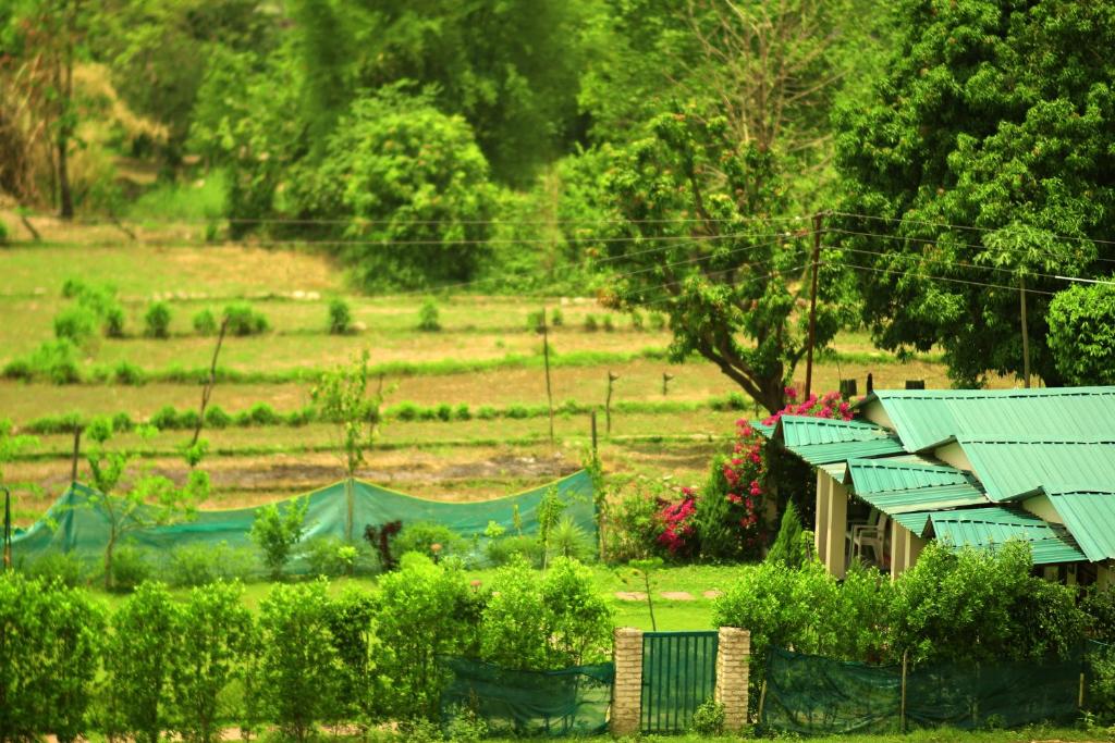 a house with a green roof in a field at Entire Farm house in Jim Corbett with staff and cook in Rāmnagar
