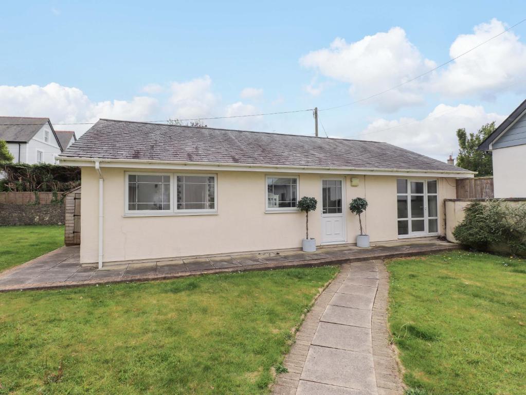 a white house with a lawn in front of it at The Bungalow in Pwllheli