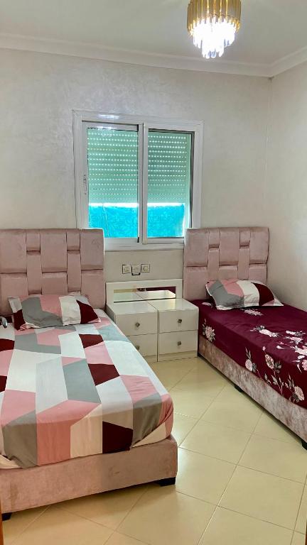a bedroom with two beds and a chandelier at Martil, Avenue Oum Kalthoum in Martil