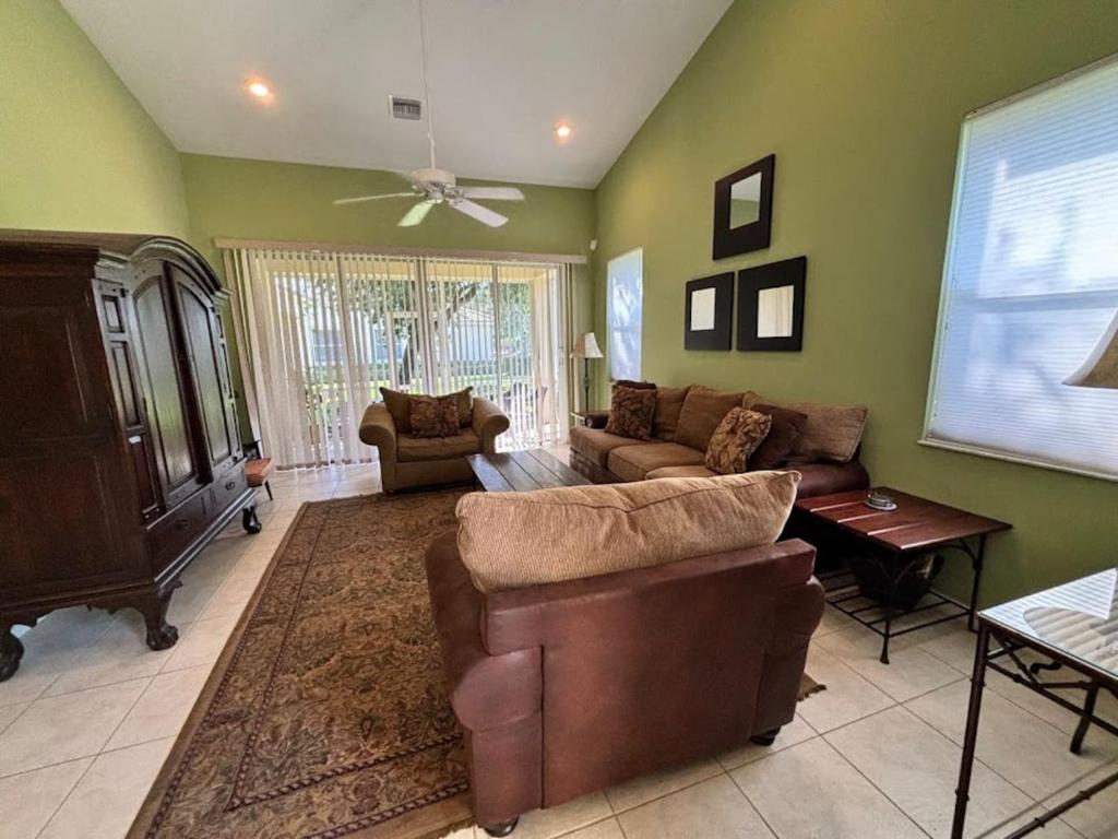 a living room with two couches and a ceiling fan at Right Direction Rentals Carnoustie Townhome in Port Saint Lucie