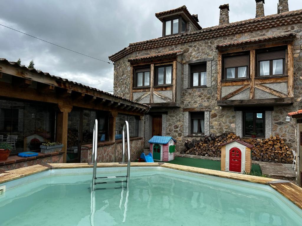 a house with a swimming pool in front of a building at Vista Bella Segovia in Tizneros