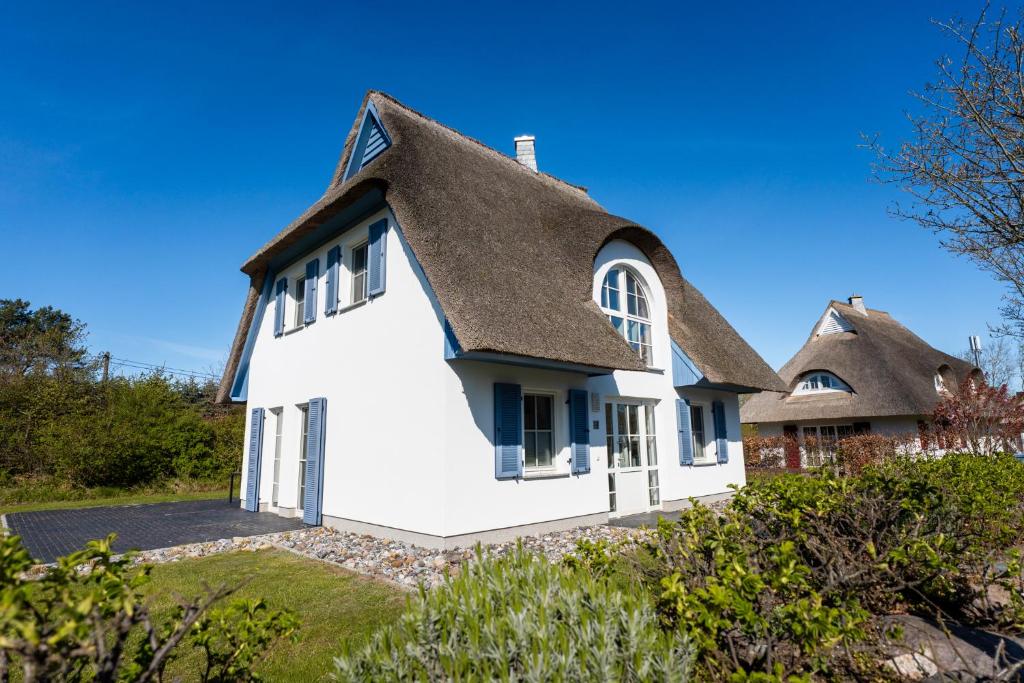 a white house with a thatched roof at Ferienhaus Schilfrohrsaenger 51 in Fuhlendorf