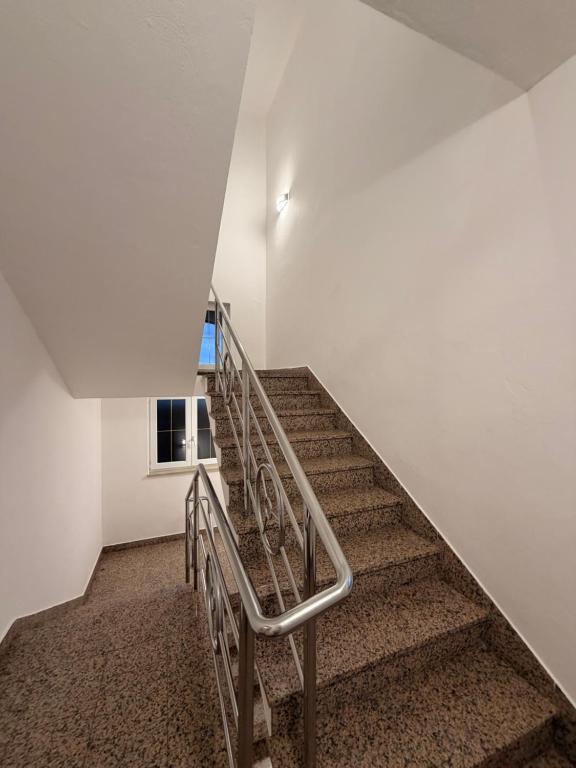 a staircase in a white room with a metal railing at Apartmani Gržeta in Vir