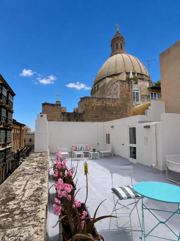 a rooftop patio with tables and chairs and a building at Carmelita in Valletta