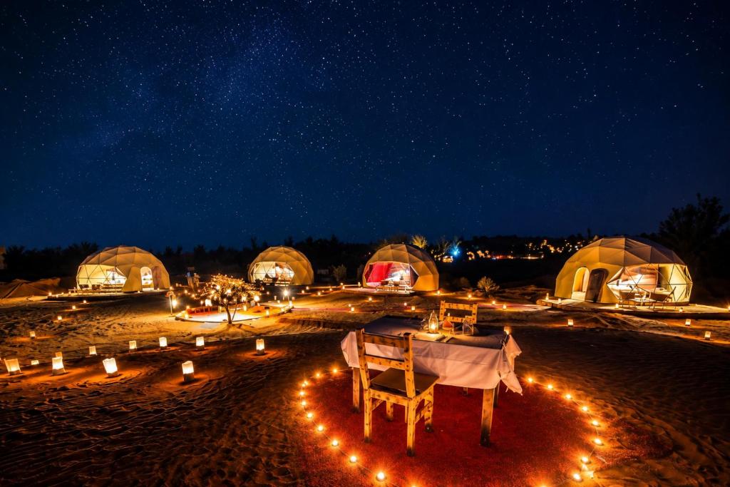 a group of tents with lights at night at Luxury Sahara Desert Glamping Experience in Merzouga in Merzouga