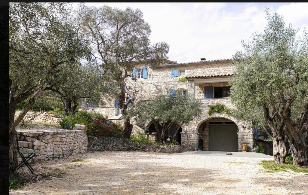a stone house with a garage and some trees at Gite Du Mouredon in Vallon-Pont-dʼArc