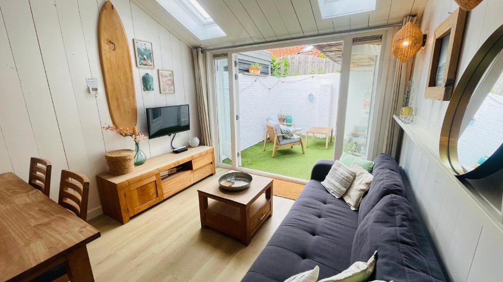 a living room with a blue couch and a tv at Kust 3 in Egmond aan Zee