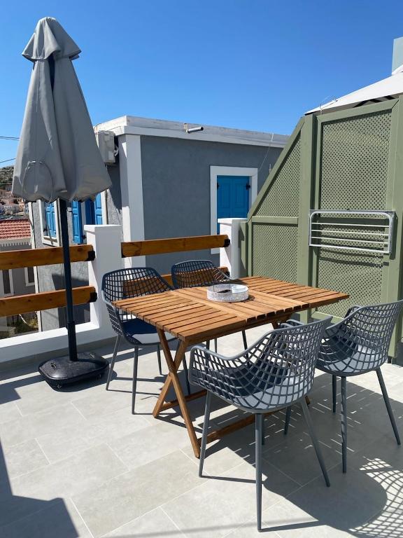 a wooden table and chairs on a patio with an umbrella at Fedon in Halki