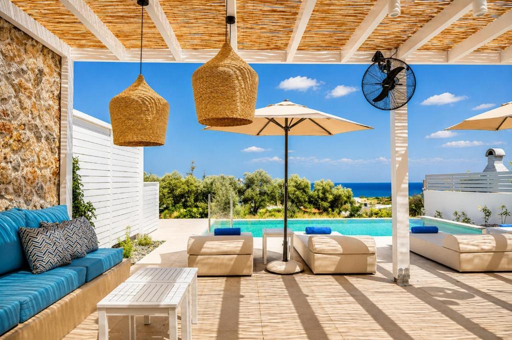 a patio with a blue couch and chairs and an umbrella at Villa Castor in Gennadi
