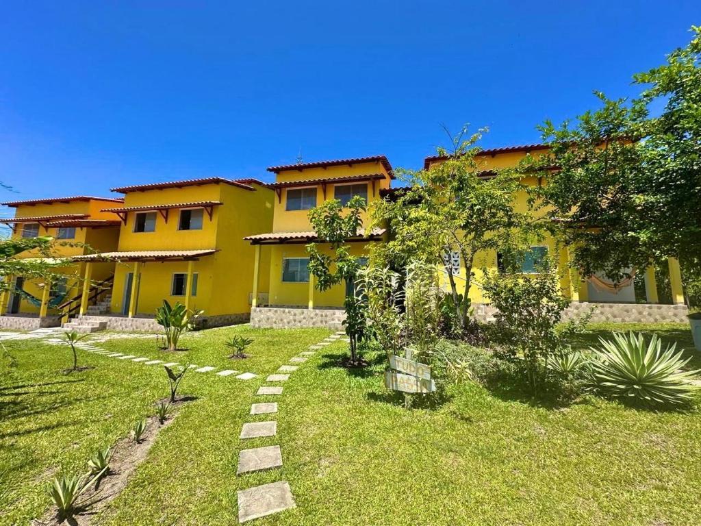 a yellow house with a garden in front of it at Ilha de Boipeba kitnets para temporada - Morada dos Pássaros Boipeba in Ilha de Boipeba